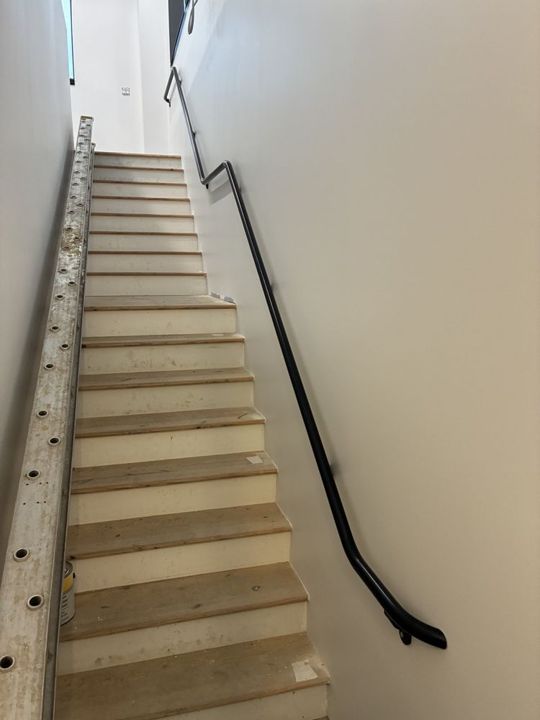 Black wall-mounted pipe handrail in Blawnox